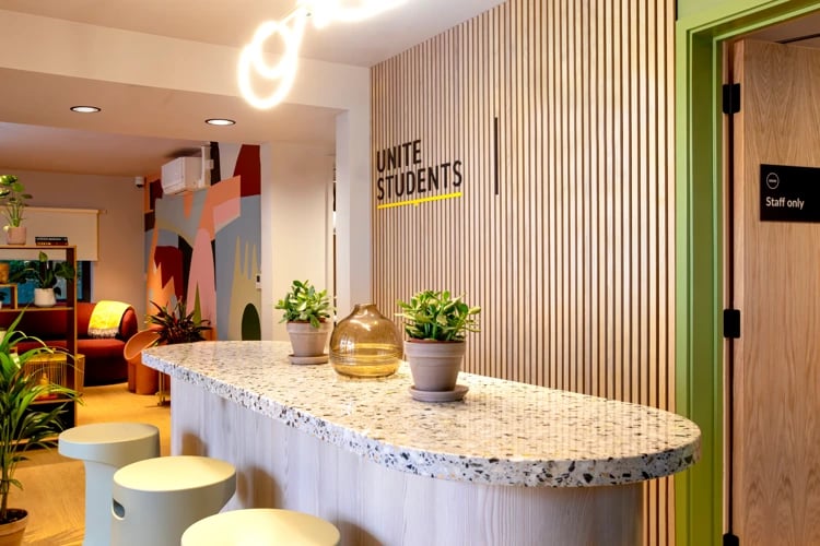 Reception desk with plants and stools common area at Pacific Court in London Student Accommodation