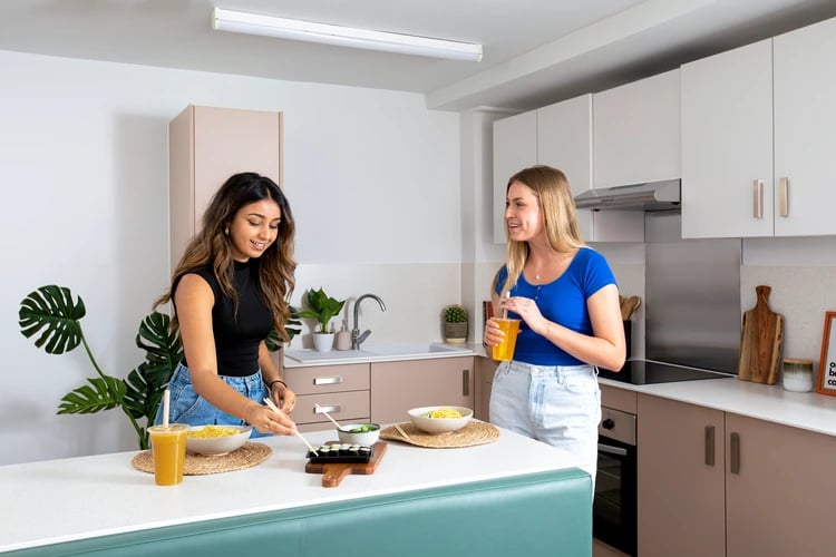 Two women with food in a modern kitchen kitchen at Pacific Court in London Student Accommodation