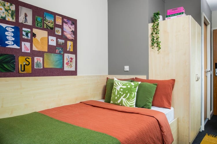 Bed with orange and green covers and art bedroom at Pacific Court in London Student Accommodation