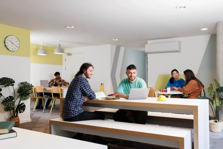 Students studying laptops and books communal area at Newgate Court in Newcastle Upon Tyne Student Accommodation