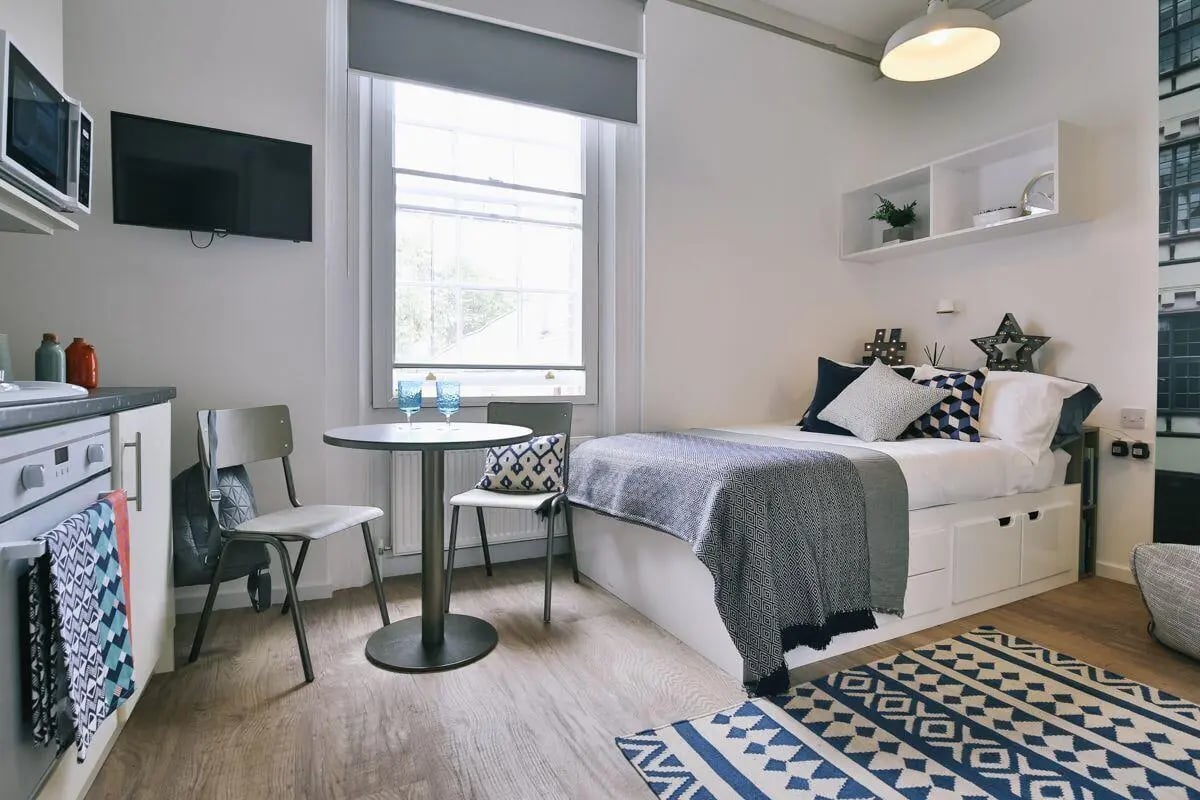 Bed microwave small table chairs studio apartment at Claremont Place in Newcastle Upon Tyne Student Accommodation