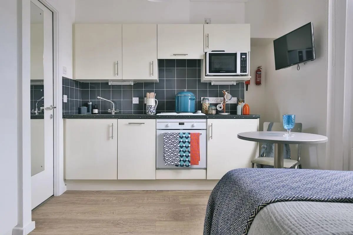 White cabinets microwave oven sink stovetop kitchen at Claremont Place in Newcastle Upon Tyne Student Accommodation
