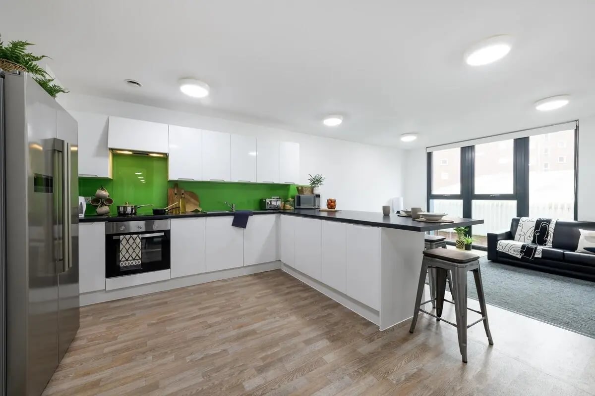 Modern white kitchen with island and seating area at Glassworks - Liverpool in Liverpool Student Accommodation