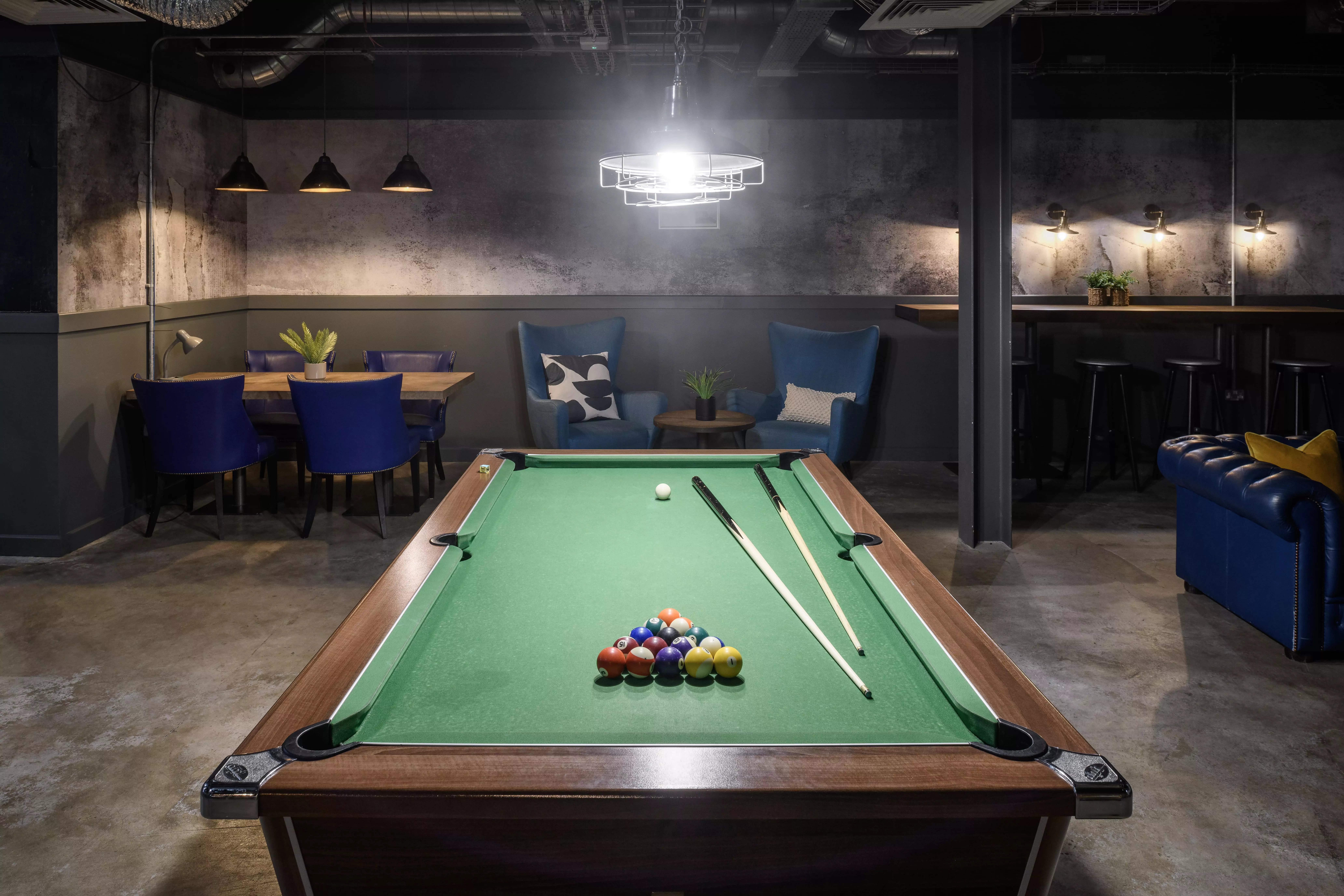 Pool table cues and balls near seating area and bar stools playing area at Hope Street in Liverpool Student Accommodation