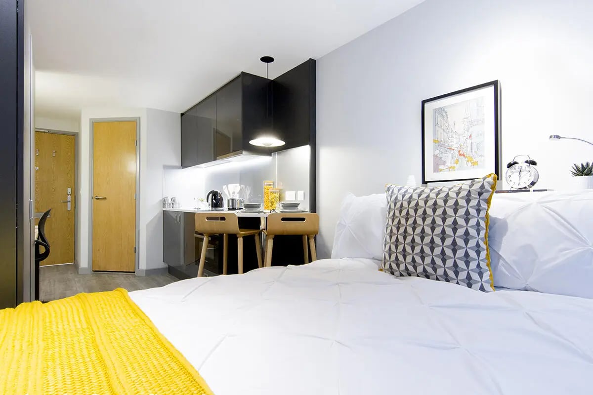 Bed kitchen area with table and chairs Studio Apartment at Yugo Therese House in London Student Accommodation