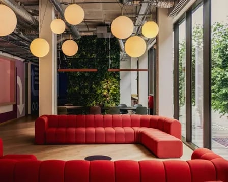Red sectional sofa with large pendant lights living room at Scape Mile End in London Student Accommodation