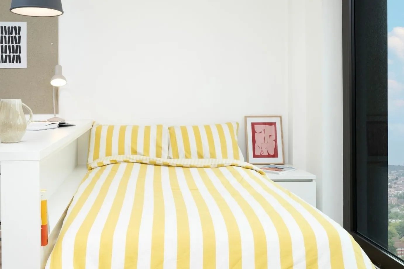 Bed with yellow striped duvet art and lamp bedroom at Scape Mile End in London Student Accommodation