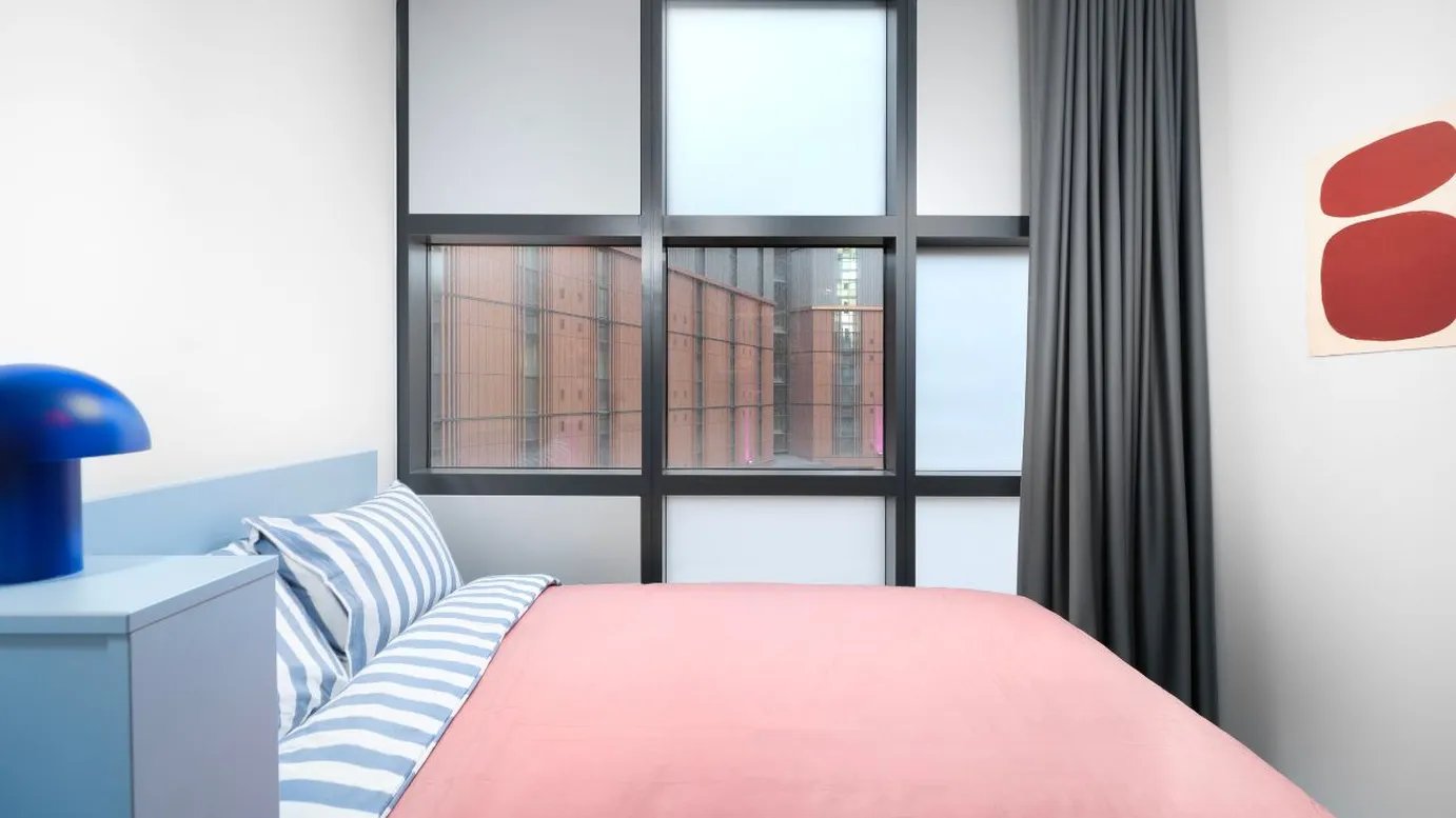 Blue lamp pink duvet striped pillows bedroom at Scape Mile End in London Student Accommodation