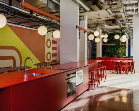 Modern red kitchen with bar stools and seating area kitchen at Scape Mile End in London Student Accommodation