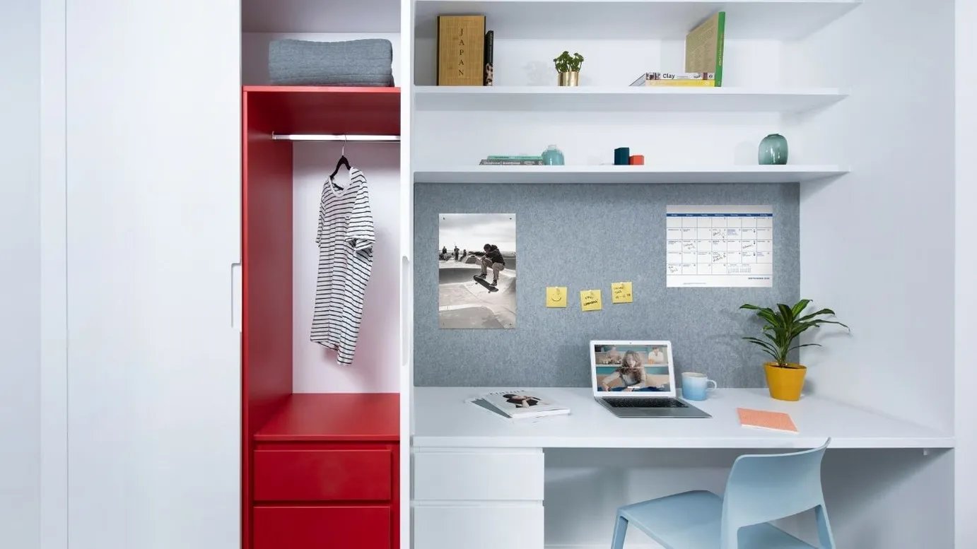 Wardrobe desk laptop calendar plant and chair study area at Scape Mile End in London Student Accommodation