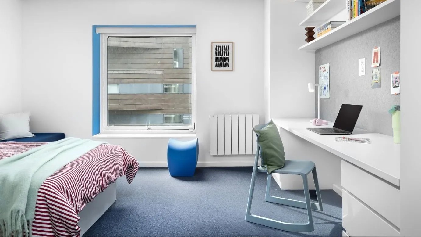 Bed desk shelves blue stool chair bedroom at Scape Mile End in London Student Accommodation
