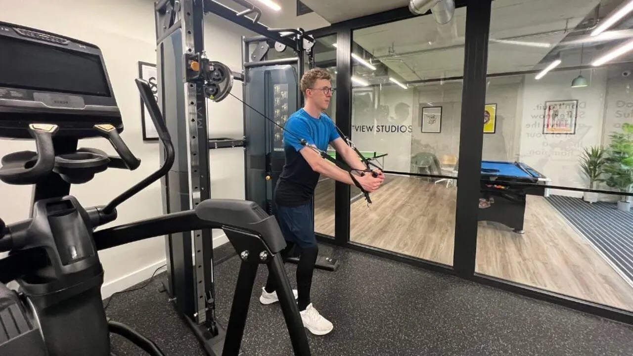 Man exercising gym equipment visible pool table area at Host View Studios in London Student Accommodation