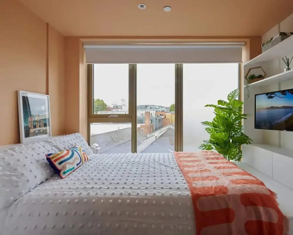 Bed with white bedding and orange throw Bedroom at Host View Studios in London Student Accommodation