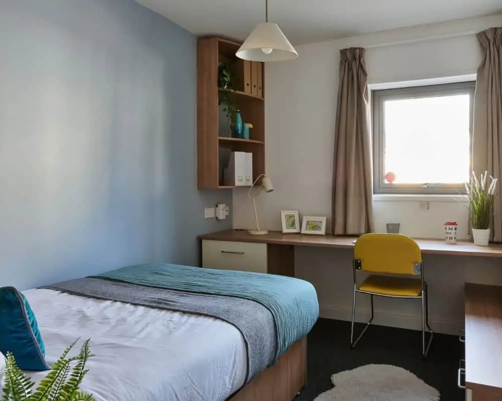 Bed desk shelf and yellow chair student bedroom at Exeter Trust House in Exeter Student Accommodation