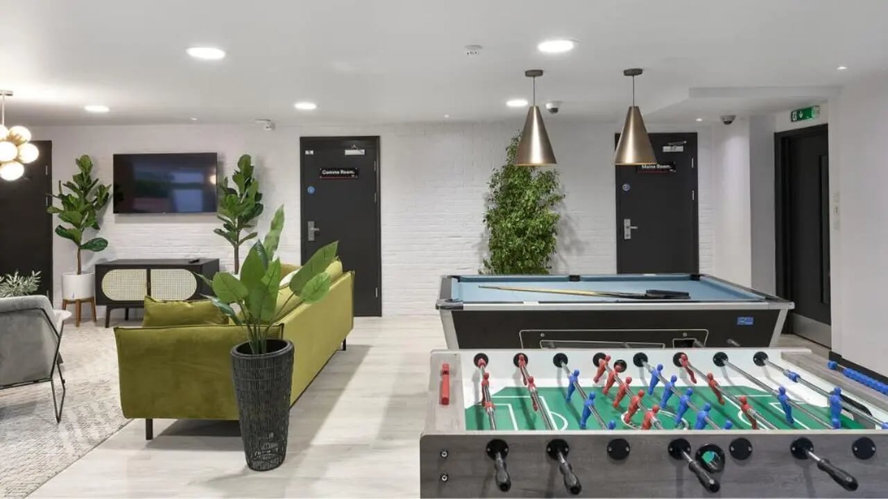 Foosball and pool tables with green sofa living area at Exeter Trust House in Exeter Student Accommodation