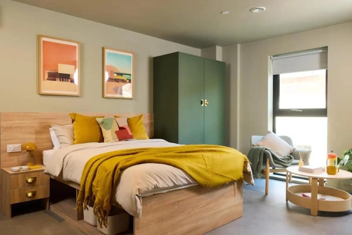 Bed with yellow blanket green wardrobe framed art bedroom at The Store House in Leeds Student Accommodation