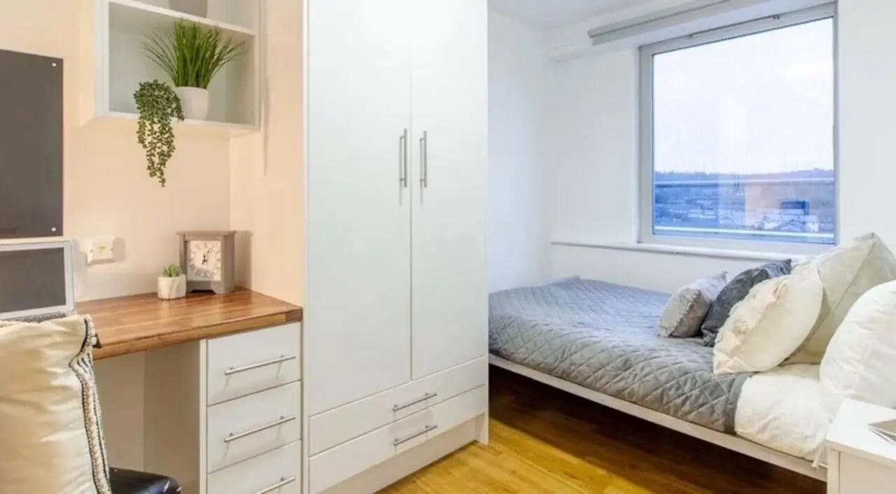 Wardrobe desk bed plants clock window Bedroom at The Glasshouse in Nottingham Student Accommodation