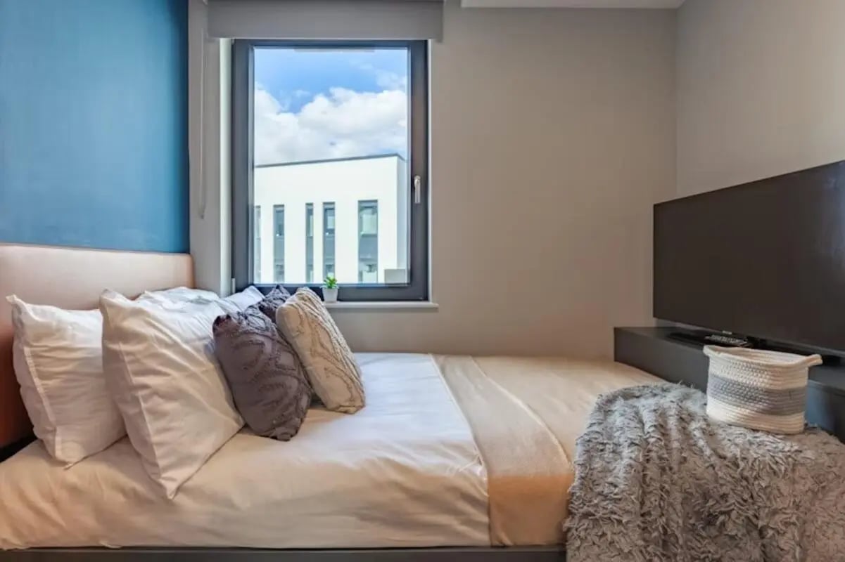 Bed pillows blanket television basket bedroom at Luxurio in Loughborough Student Accommodation