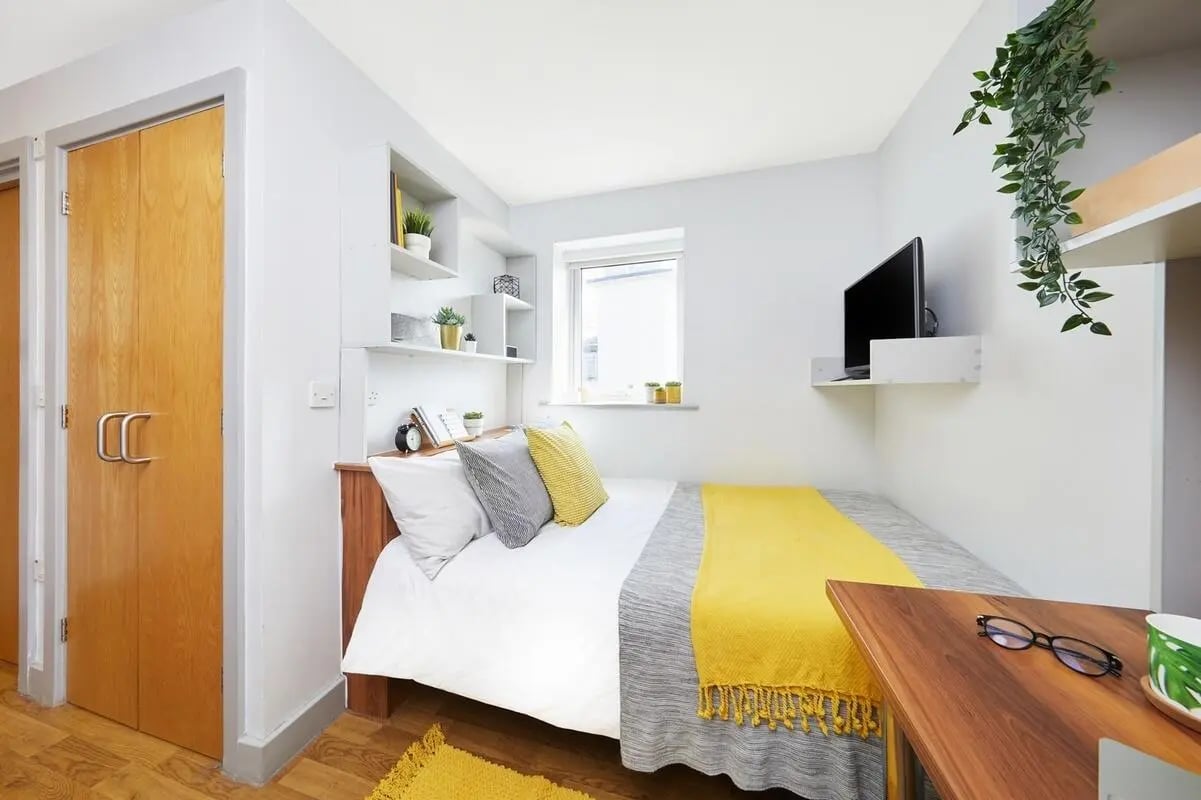Bed with yellow blanket shelves TV bedroom at Collegiate St James Street in Portsmouth Student Accommodation