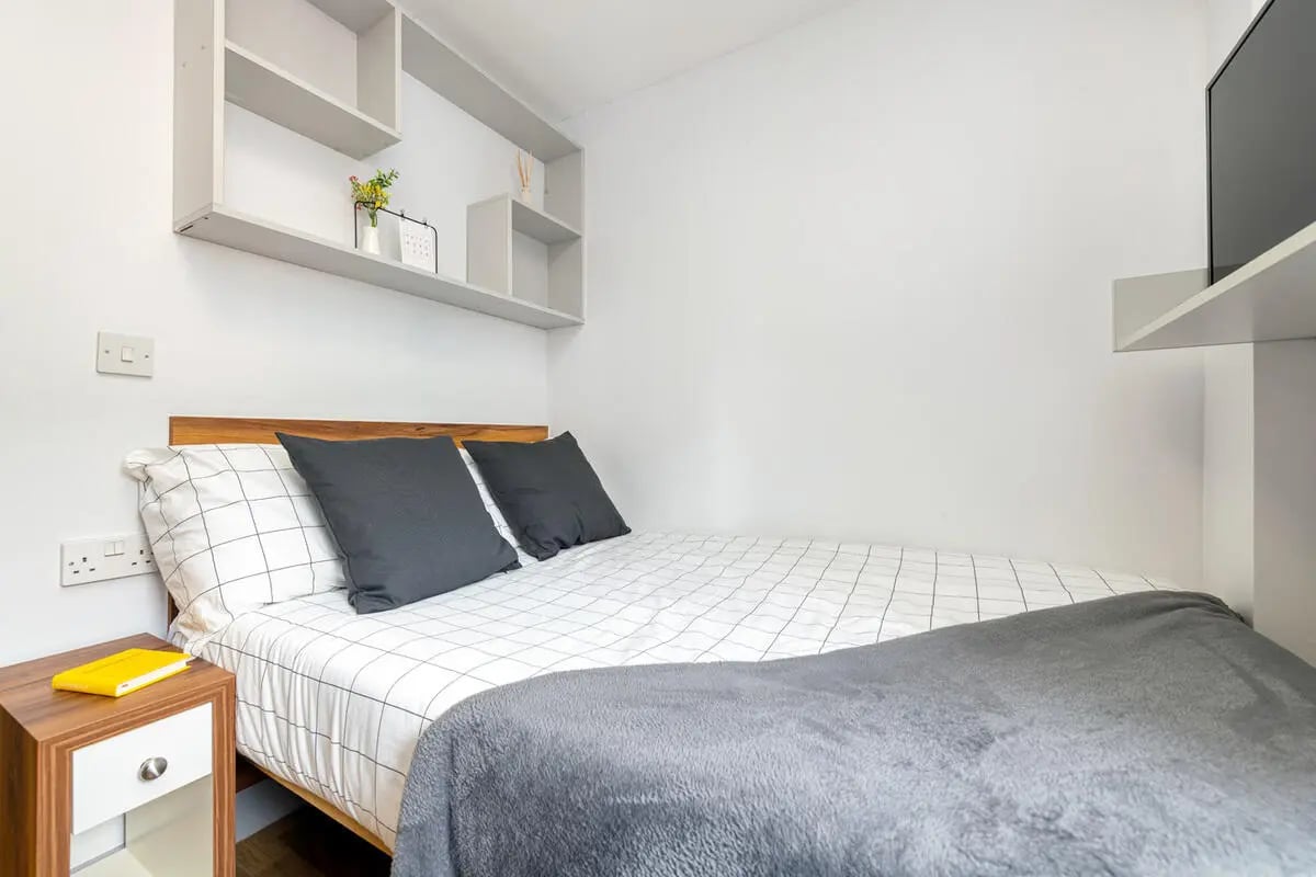 Bed with grey pillows and shelves bedroom at Collegiate St James Street in Portsmouth Student Accommodation