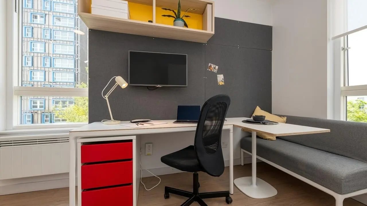 Desk chair laptop red drawers gray sofa dining area at Collegiate Middle Street in Portsmouth Student Accommodation