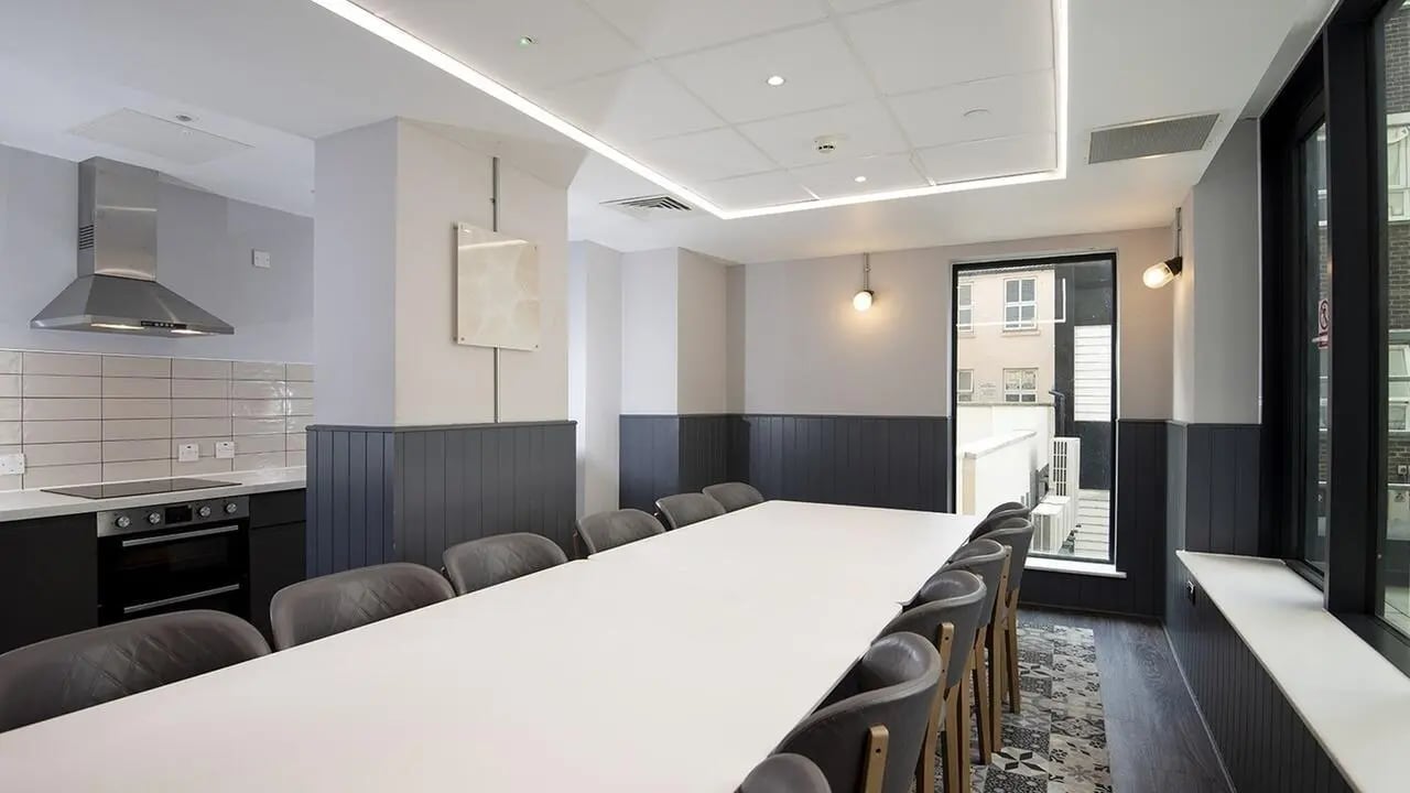 Large table and chairs with kitchen area communal room at Collegiate Crown Place Portsmouth in Portsmouth Student Accommodation