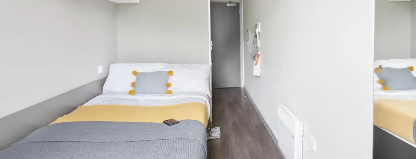Bed with grey pillow yellow throw and phone bedroom at Gosford Gate in Coventry Student Accommodation