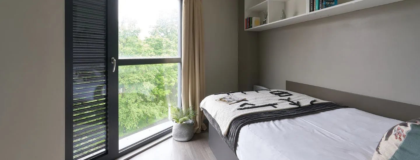 Bed with blanket window plant shelf books bedroom at Gosford Gate in Coventry Student Accommodation