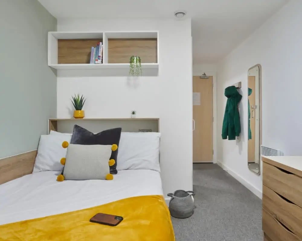Bed with yellow blanket shelves and doorway bedroom at Sky Blue Point in Coventry Student Accommodation