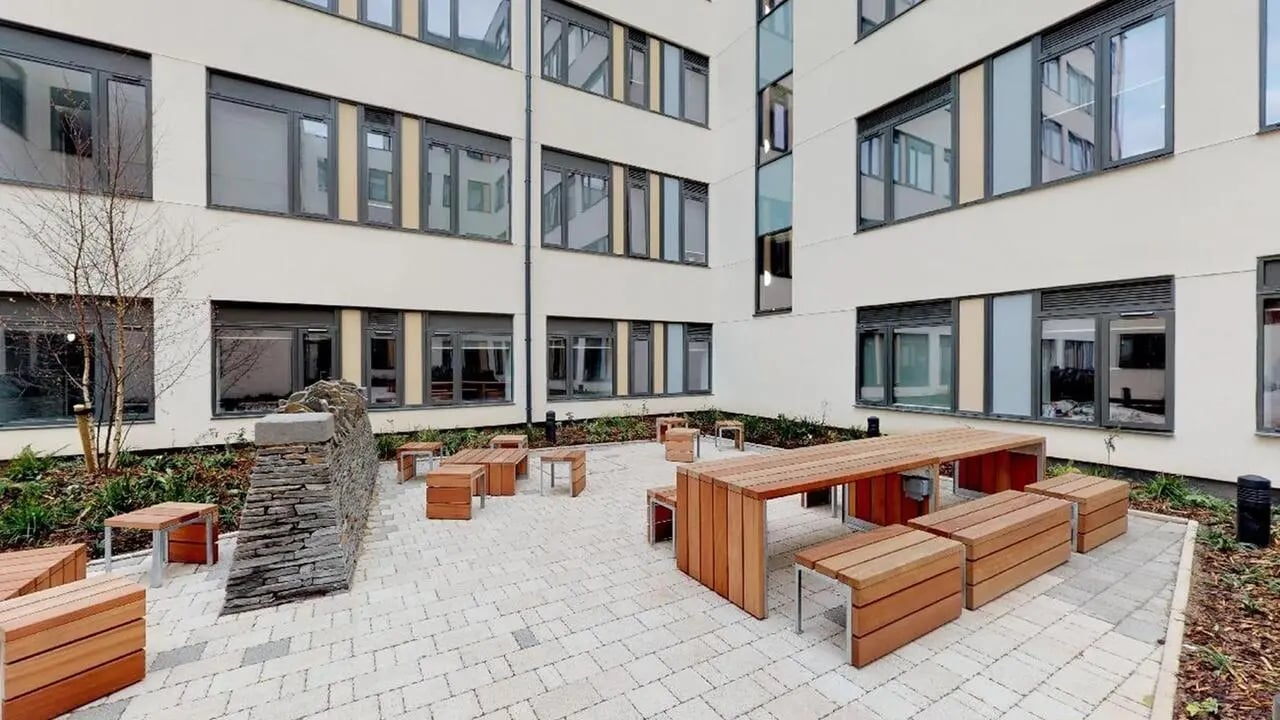 Wooden benches tables stone wall courtyard exterior at Collegiate Crown Place Cardiff in Cardiff Student Accommodation
