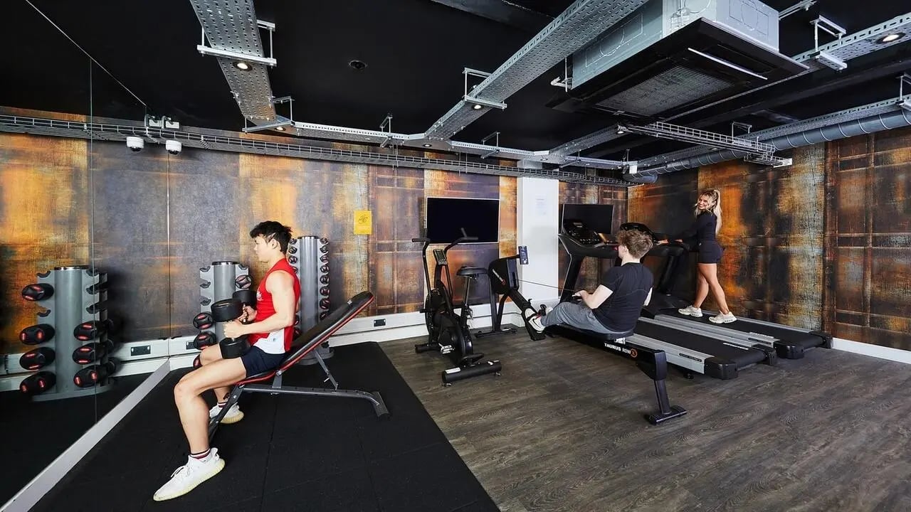 People exercising in a gym with treadmills and weights gym at Collegiate Crown Place Cardiff in Cardiff Student Accommodation