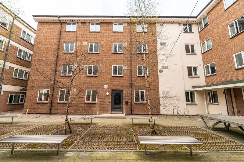 Brick building with many windows and benches exterior at AXO Sherbourne Student Village in Coventry Student Accommodation