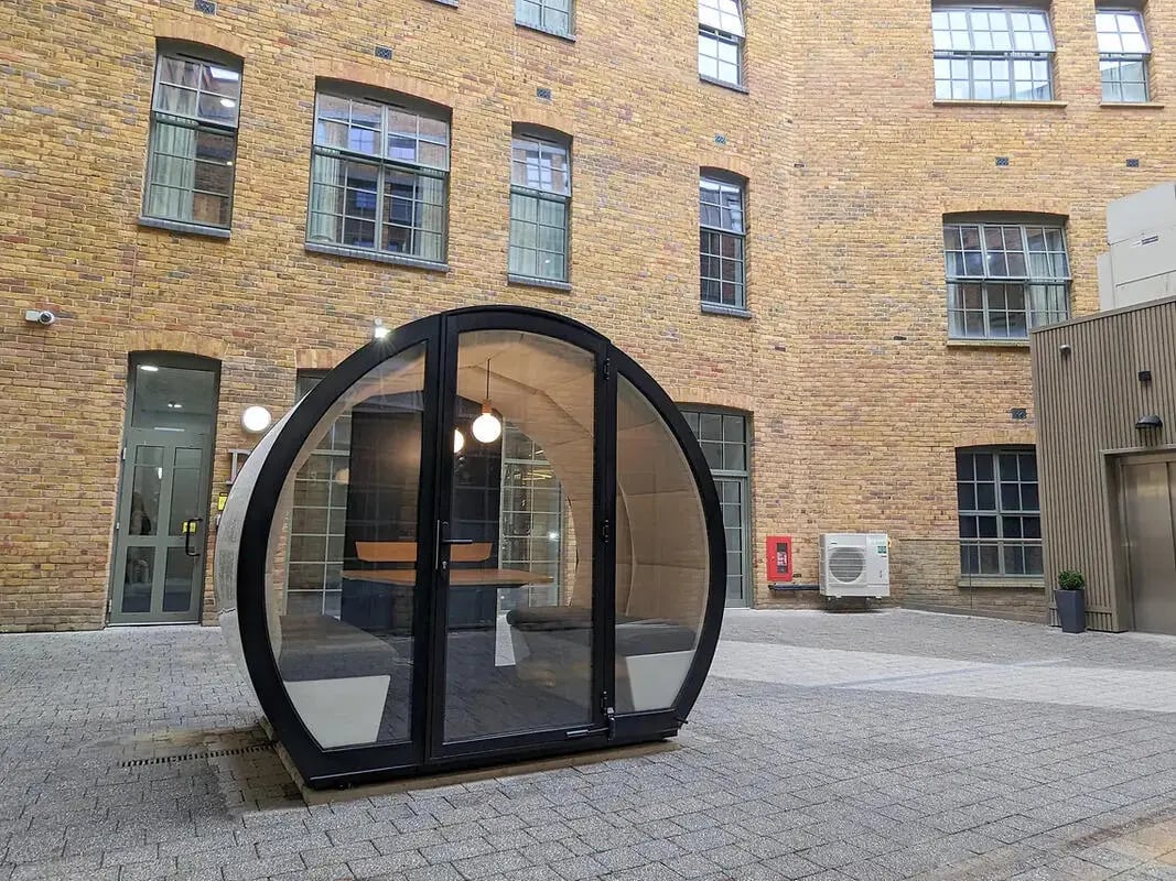 Glass pod with seating and table outdoor room at Depot Point in London Student Accommodation