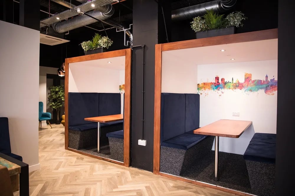 Booth seating with tables and city mural communal area at City Heights - Cardiff in Cardiff Student Accommodation