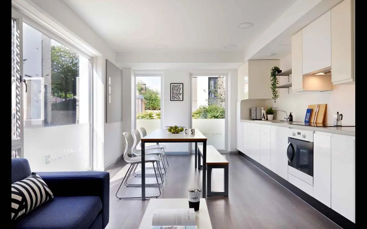 Blue sofa dining table and white kitchen living room at Hampton Square in Southampton Student Accommodation