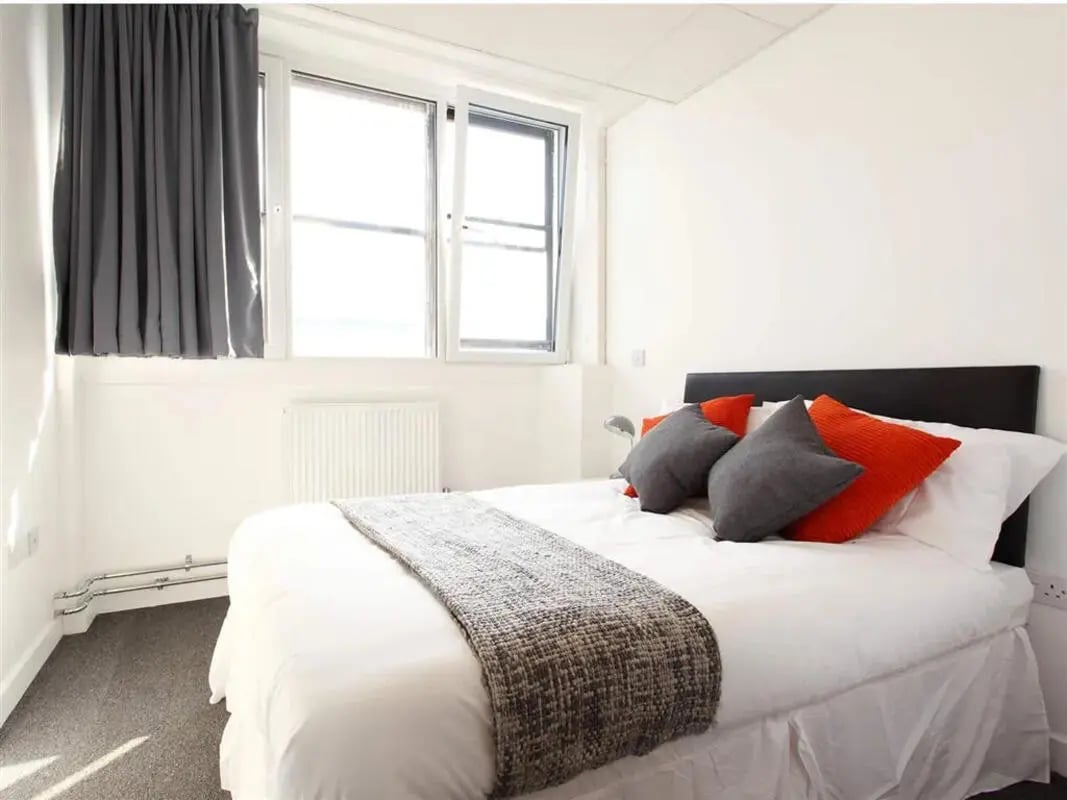 Bed with orange grey pillows and blanket bedroom at Glasgow West-End in Glasgow Student Accommodation