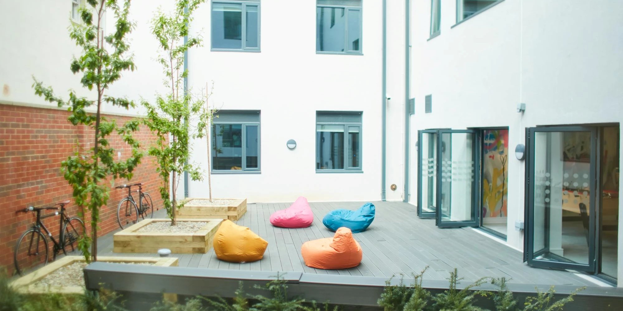 Beanbags bicycles and trees in courtyard Exterior at Canvas Student - Quintana Gate in Exeter Student Accommodation