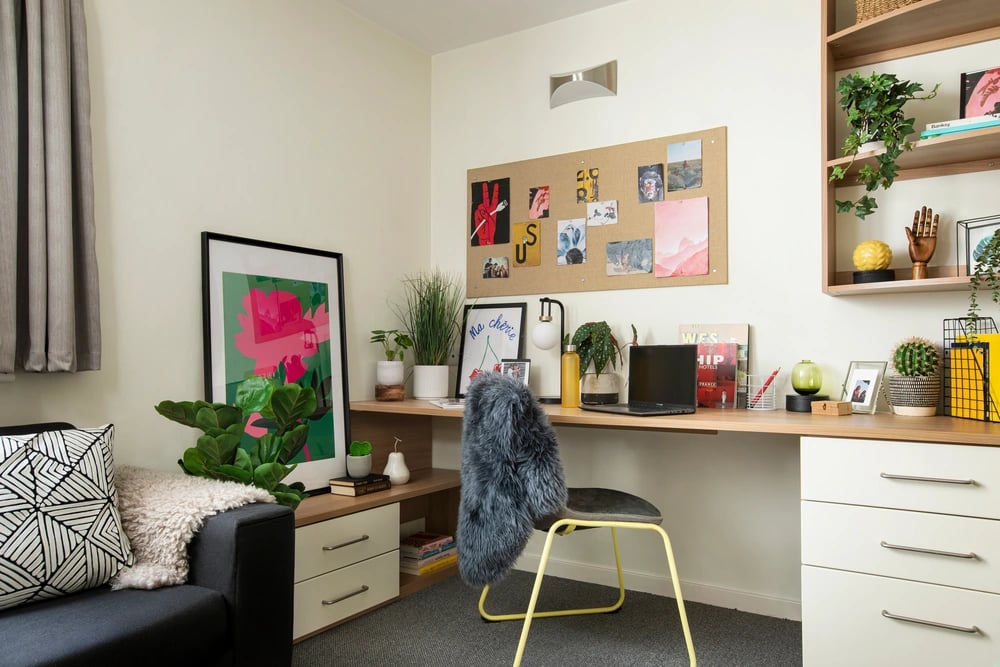Desk with laptop plants framed art and chair study area at Moonraker Point in London Student Accommodation