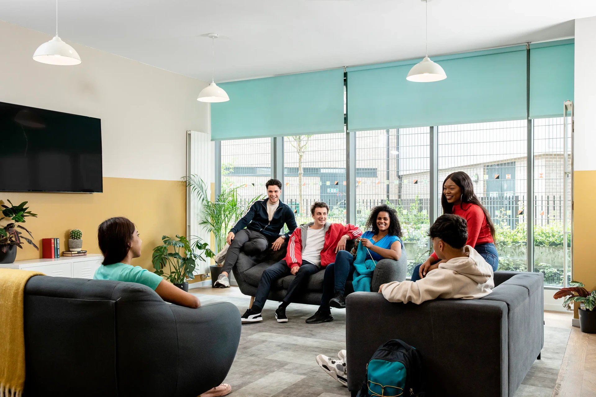Students relaxing on sofas with plants and TV living room at Moonraker Point in London Student Accommodation