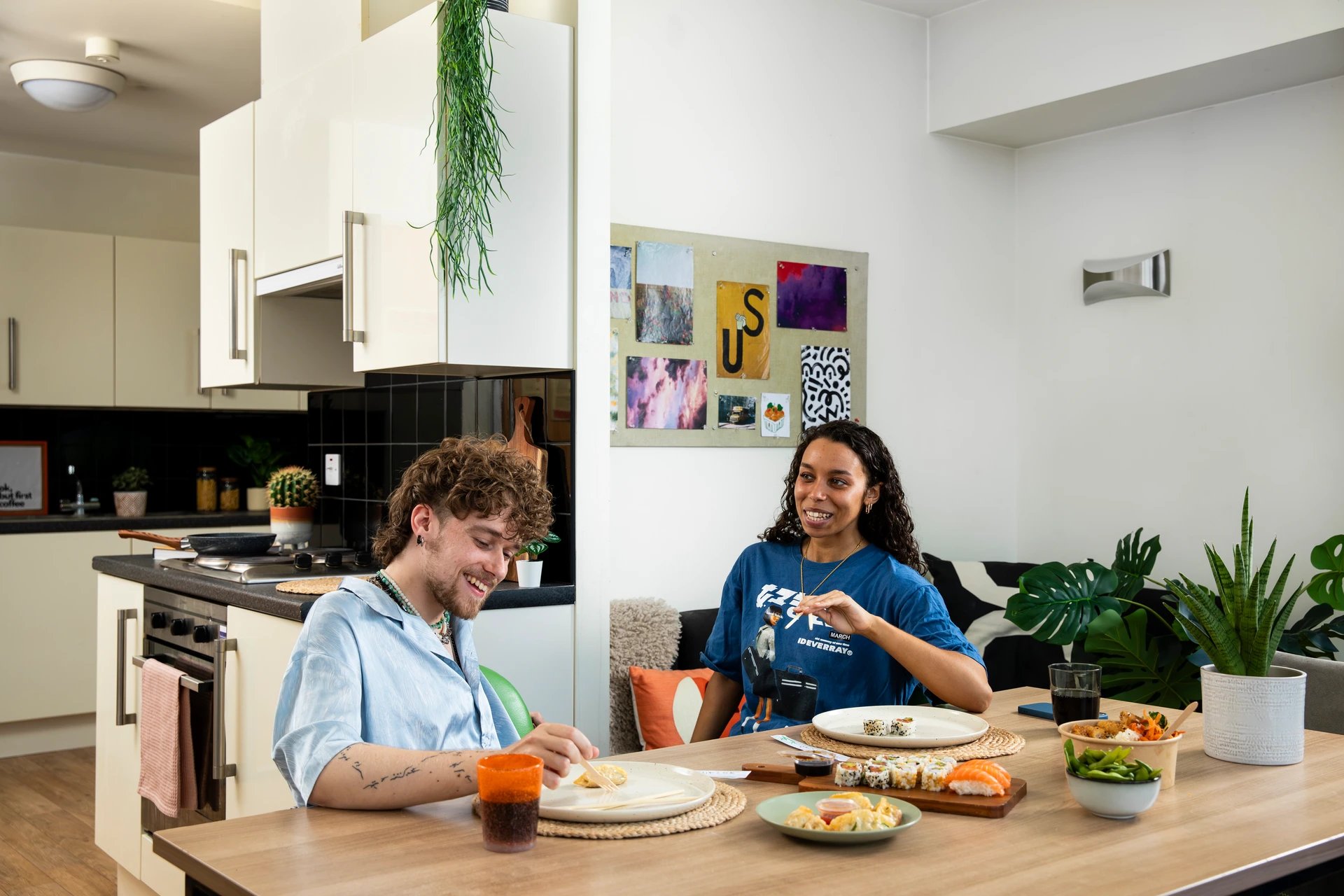 Two students eat sushi at kitchen table living room at Moonraker Point in London Student Accommodation