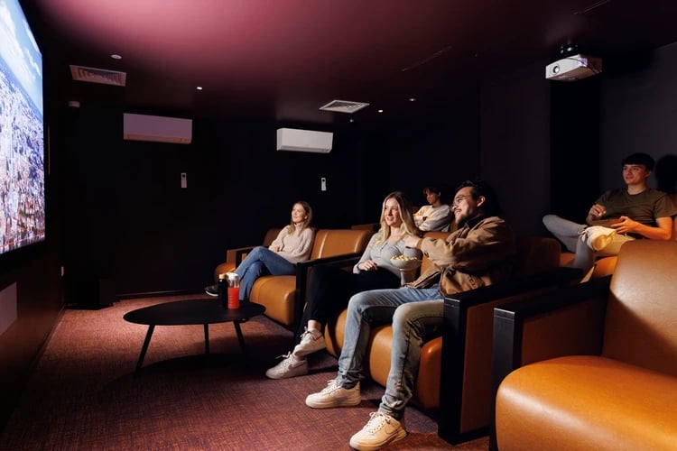 People watch movie on sofa in cinema room at Stratford One in London Student Accommodation