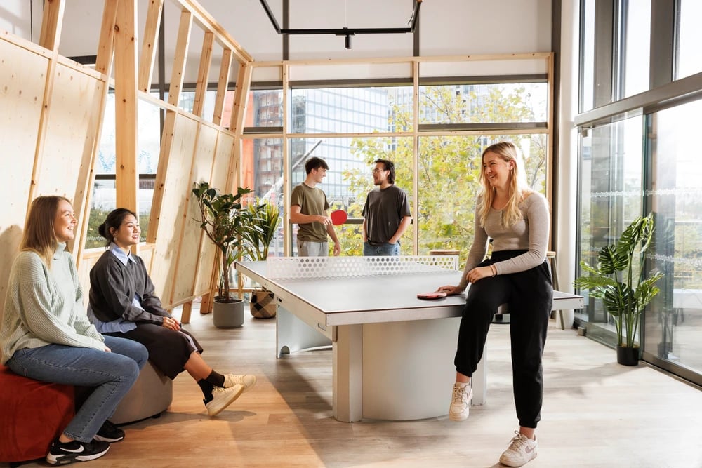 Students play ping pong with natural light living area at Stratford One in London Student Accommodation