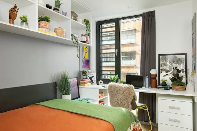 Desk with laptop shelving plants artwork bedroom exterior at Campbell House in Bristol Student Accommodation