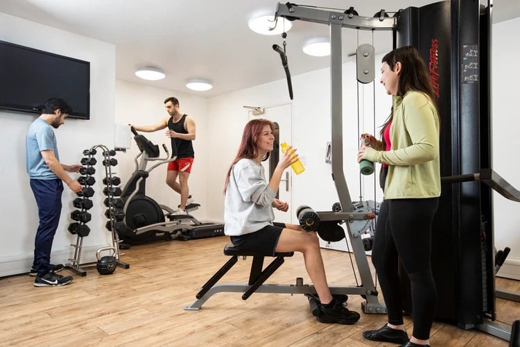 Students exercising on equipment with dumbbells gym at Walmsley Studios in London Student Accommodation