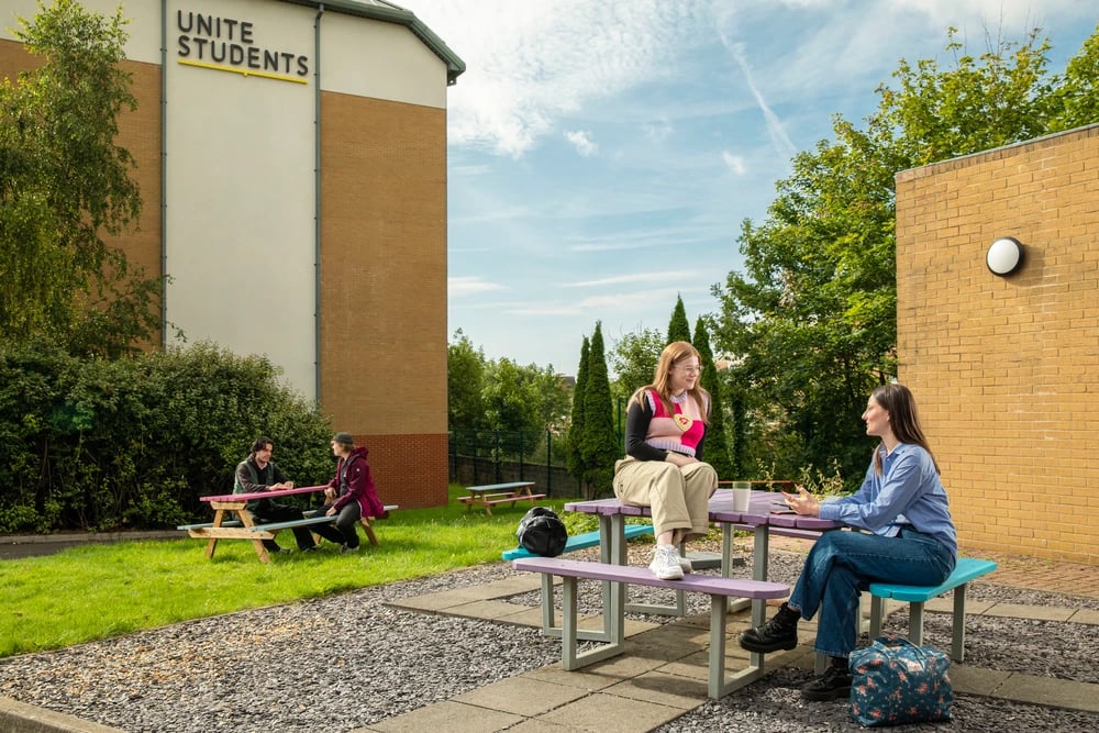 Students sitting at picnic tables outdoors exterior at Cambrian Point in Cardiff Student Accommodation