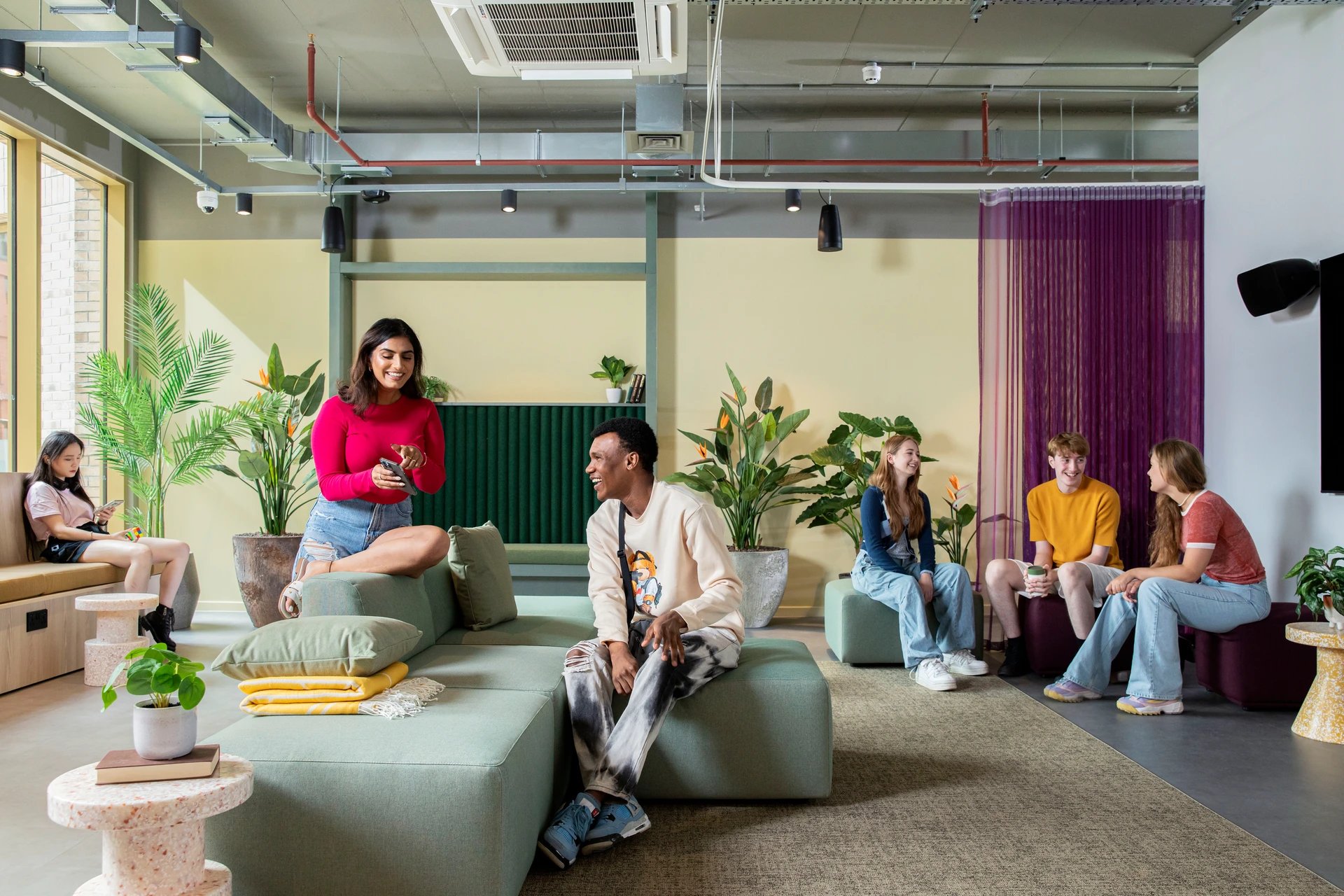 Students relaxing on sofas with plants living room at Cambrian Point in Cardiff Student Accommodation