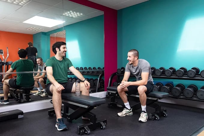 Men talking on gym benches near weights gym at Adam Street Gardens in Cardiff Student Accommodation