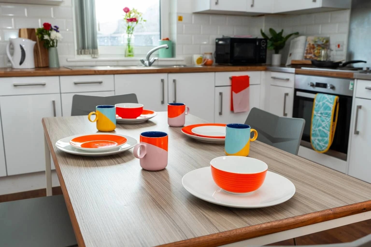 Table setting with colorful mugs plates bowls kitchen at Tramways - Salford in Salford Student Accommodation