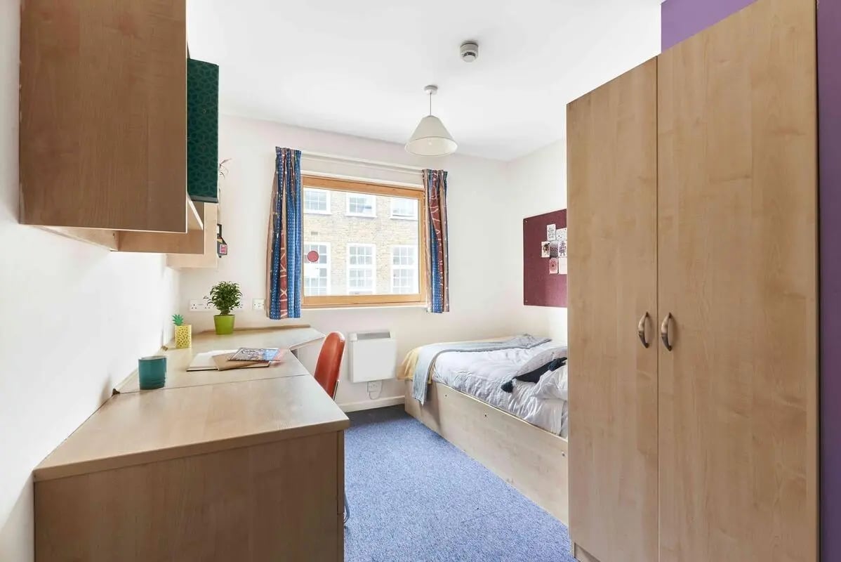 Bed desk wardrobe and purple wall bedroom at Bernard Myers House in London Student Accommodation