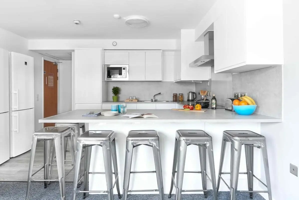 Modern kitchen with stools and fruit bowl kitchen at Bernard Myers House in London Student Accommodation